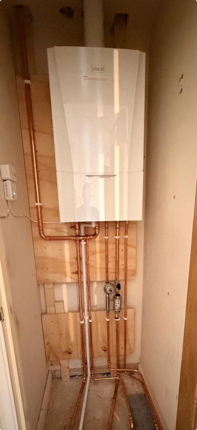Boiler mounted on a plywood backboard with new pipework